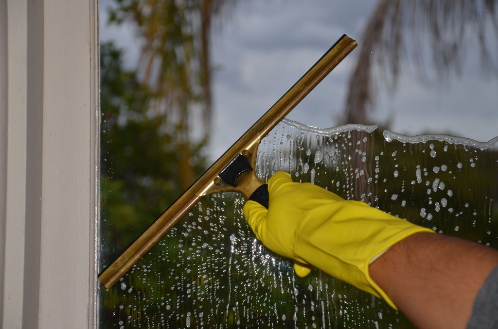 Professional window washing with a squeegee on a residential window